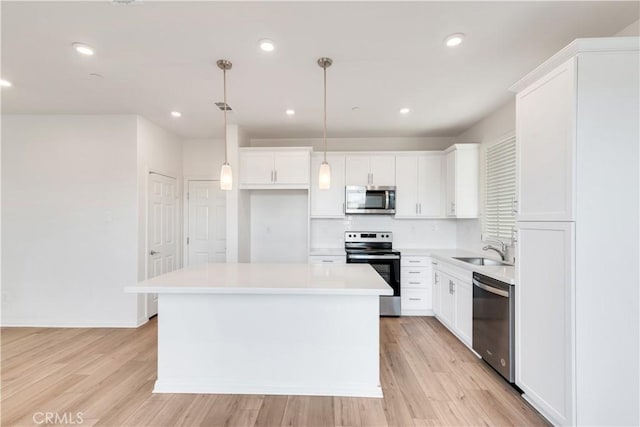 501 Pablo Rd Unit 48, Lake Elsinore, CA 92530 - kitchen featuring appliances with stainless steel finishes, white cabinetry, a center island, light countertops, and light wood-type flooring