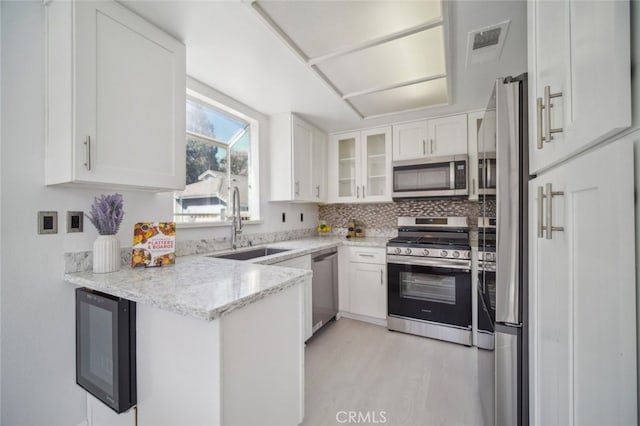 26970 Flo Ln Unit 310, Canyon Country, CA 91351 - kitchen with stainless steel appliances, white cabinetry, light stone counters, backsplash, and glass insert cabinets