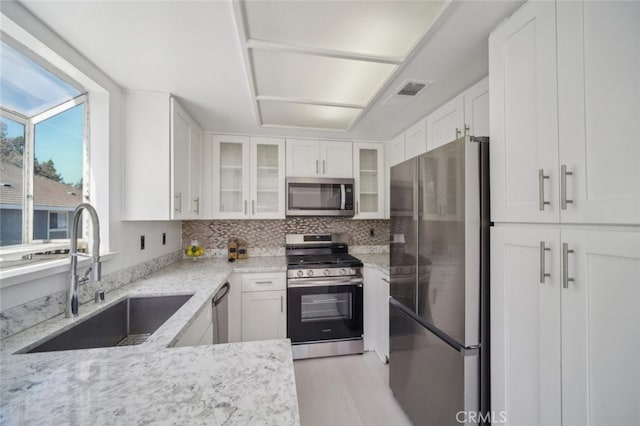 26970 Flo Ln Unit 310, Canyon Country, CA 91351 - kitchen featuring appliances with stainless steel finishes, white cabinetry, light stone counters, and decorative backsplash