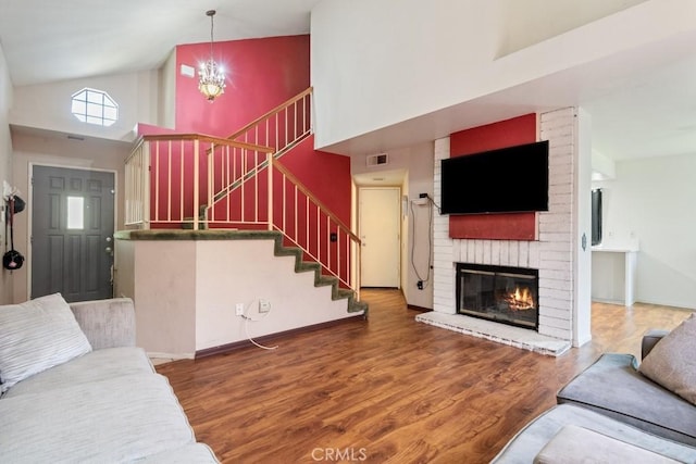 14625 Mountain High Dr, Fontana, CA 92337 - living room featuring high vaulted ceiling, stairway, a brick fireplace, wood finished floors, and a chandelier