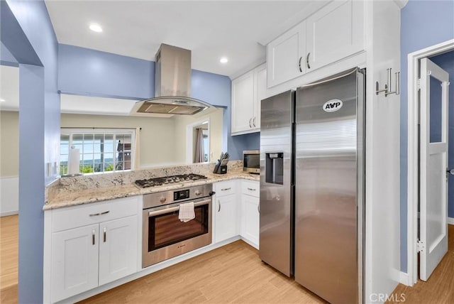 918 Dorothea Rd, La Habra Heights, CA 90631 - kitchen featuring appliances with stainless steel finishes, island range hood, light wood-style floors, white cabinets, and light stone counters