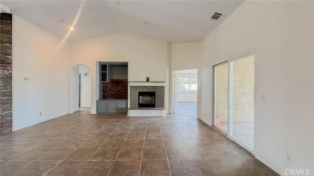 11126 Arena Rd, Pinon Hills, CA 92372 - unfurnished living room with arched walkways, a fireplace with raised hearth, high vaulted ceiling, and tile patterned floors