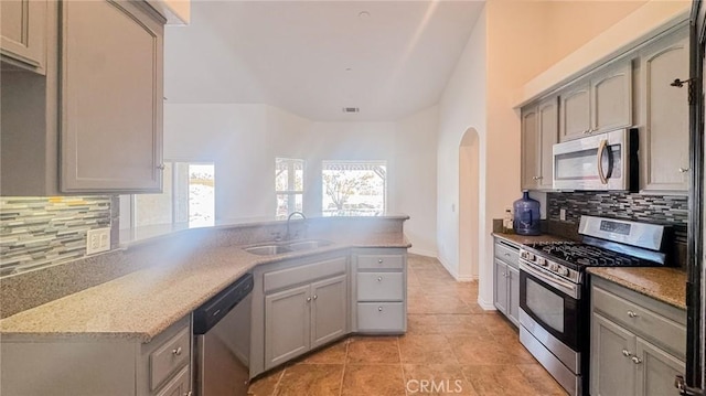 11126 Arena Rd, Pinon Hills, CA 92372 - kitchen with stainless steel appliances, a peninsula, arched walkways, decorative backsplash, and gray cabinets
