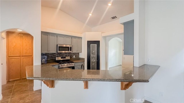 11126 Arena Rd, Pinon Hills, CA 92372 - kitchen with stainless steel appliances, arched walkways, a breakfast bar area, decorative backsplash, and dark stone counters
