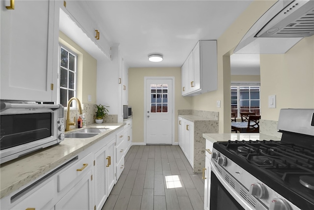 6059 Riverside Ave, Huntington Park, CA 90255 - kitchen with stainless steel appliances, white cabinetry, light stone countertops, and ventilation hood