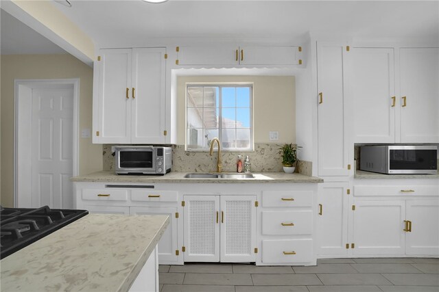 6059 Riverside Ave, Huntington Park, CA 90255 - kitchen with stainless steel microwave, light tile patterned floors, white cabinets, and tasteful backsplash