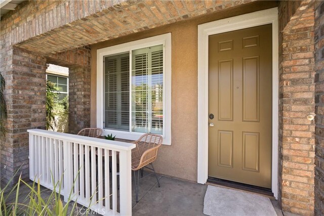 154 Fernpine Ln, Pomona, CA 91767 - property entrance featuring covered porch, brick siding, and stucco siding