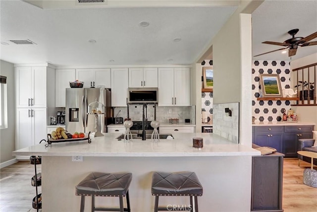 2000 San Antonio Dr, Corona, Corona, CA 92882 - kitchen featuring appliances with stainless steel finishes, light wood-style floors, a breakfast bar, and backsplash