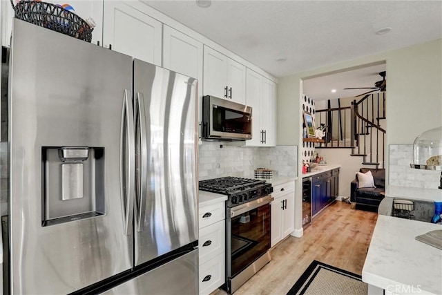 2000 San Antonio Dr, Corona, Corona, CA 92882 - kitchen featuring appliances with stainless steel finishes, white cabinetry, tasteful backsplash, light wood finished floors, and a ceiling fan