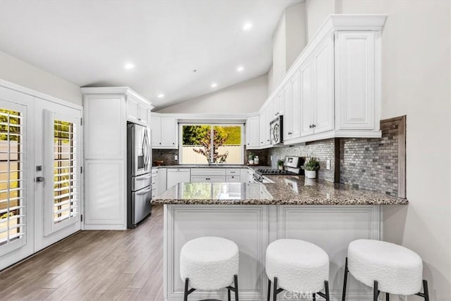 33554 Halyard Dr, Dana Point, CA 92629 - kitchen with appliances with stainless steel finishes, a peninsula, dark stone countertops, tasteful backsplash, and lofted ceiling