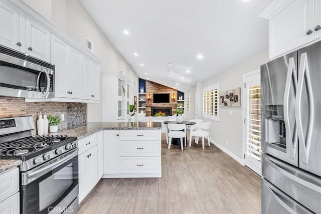 33554 Halyard Dr, Dana Point, CA 92629 - kitchen featuring appliances with stainless steel finishes, ceiling fan, a fireplace, vaulted ceiling, and tasteful backsplash