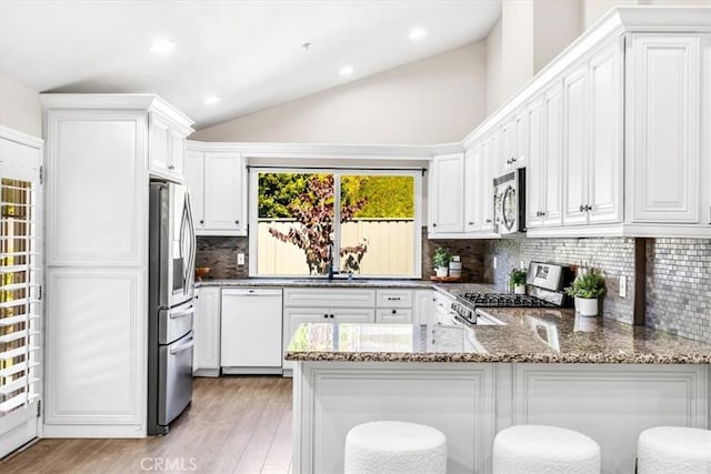 33554 Halyard Dr, Dana Point, CA 92629 - kitchen with appliances with stainless steel finishes, a peninsula, light wood-style floors, stone countertops, and lofted ceiling