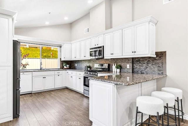 33554 Halyard Dr, Dana Point, CA 92629 - kitchen with appliances with stainless steel finishes, a peninsula, light wood-style floors, backsplash, and high vaulted ceiling