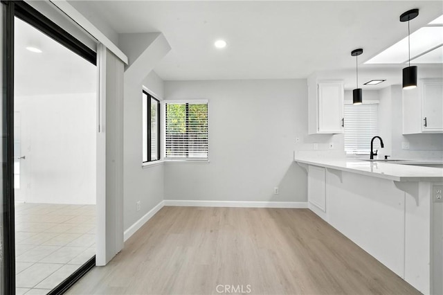 10655 Springfield Dr, Rancho Cucamonga, CA 91730 - kitchen with light wood finished floors, light countertops, a breakfast bar, white cabinetry, and recessed lighting