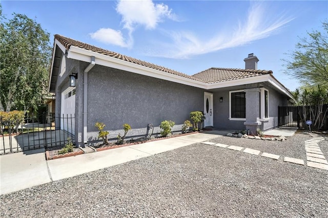 10655 Springfield Dr, Rancho Cucamonga, CA 91730 - view of side of home with a garage, a chimney, driveway, stucco siding, and a tiled roof