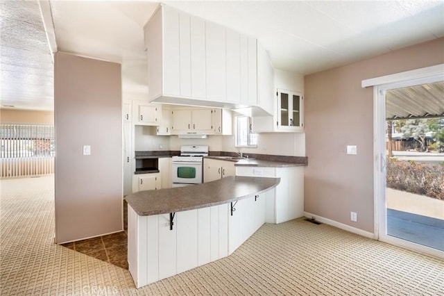 32540 San Miguelito Dr, Thousand Palms, CA 92276 - kitchen with white range, dark countertops, a peninsula, and light carpet