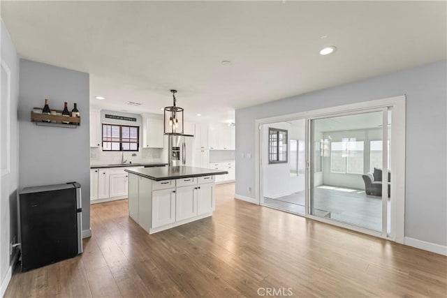 19408 Campaign Dr, Carson, CA 90746 - kitchen featuring stainless steel refrigerator with ice dispenser, white cabinets, dark countertops, light wood-style floors, and recessed lighting