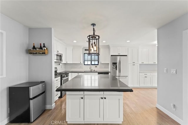19408 Campaign Dr, Carson, CA 90746 - kitchen featuring appliances with stainless steel finishes, white cabinetry, light wood-style flooring, a kitchen island, and recessed lighting