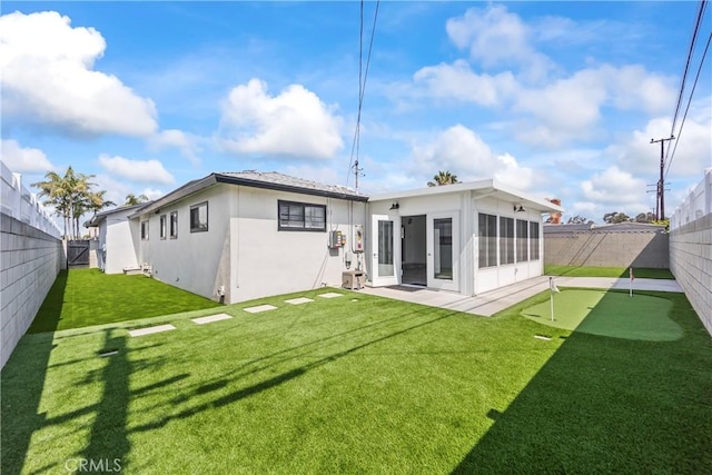 19408 Campaign Dr, Carson, CA 90746 - back of house featuring an area to practice putting, stucco siding, a fenced backyard, and a sunroom