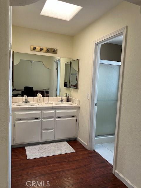 7653 Phelan Rd, Phelan, CA 92371 - full bathroom featuring wood finished floors, double vanity, and a shower with shower door
