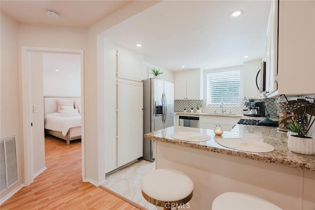 20334 Rue Crevier Unit 621, Canyon Country, CA 91351 - kitchen featuring stainless steel appliances, a peninsula, backsplash, white cabinets, and light stone countertops