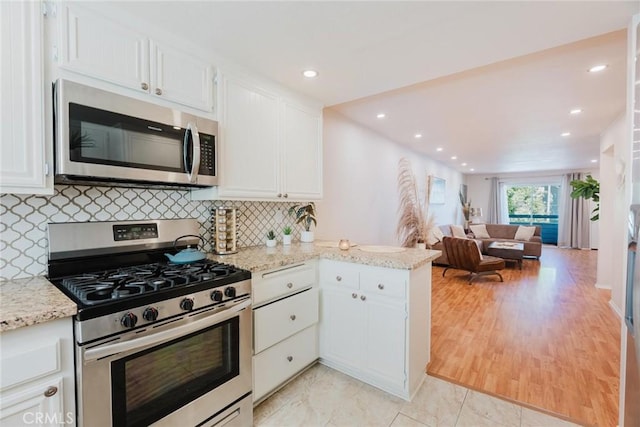 20334 Rue Crevier Unit 621, Canyon Country, CA 91351 - kitchen with appliances with stainless steel finishes, white cabinetry, open floor plan, a peninsula, and light stone countertops