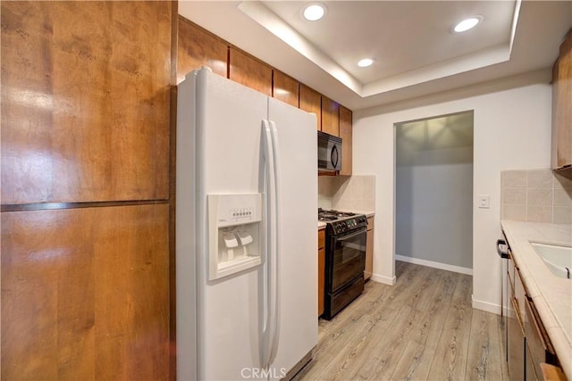 641 Piney Way Unit D, Morro Bay, CA 93442 - kitchen with black appliances, light wood-style floors, brown cabinets, recessed lighting, and a tray ceiling