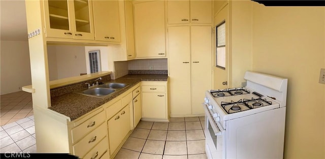 438 W Ramona Dr, Rialto, CA 92376 - kitchen with white gas range oven, light tile patterned floors, dark countertops, and backsplash