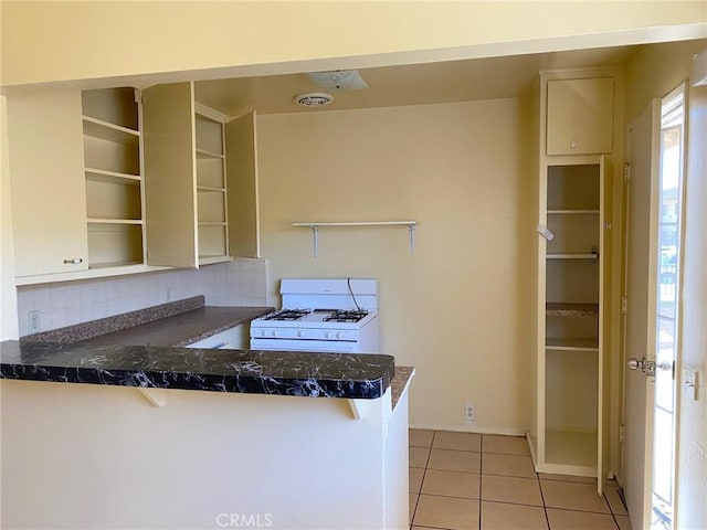 438 W Ramona Dr, Rialto, CA 92376 - kitchen with white gas range oven, open shelves, a peninsula, and light tile patterned flooring