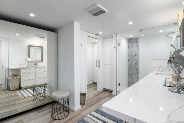 full bathroom with wood finished floors, vanity, a shower stall, and recessed lighting