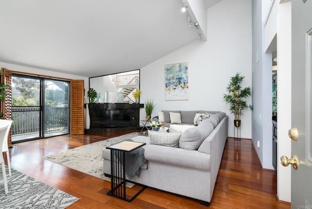 living room featuring vaulted ceiling, wood finished floors, and track lighting
