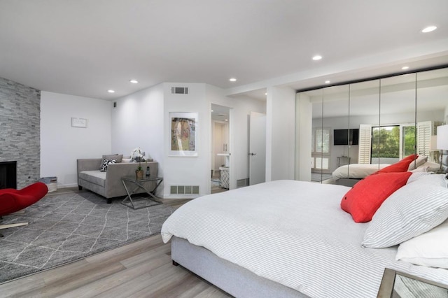 bedroom with recessed lighting, wood finished floors, and a fireplace