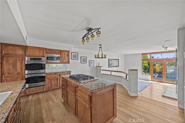 4 Woodhaven, Laguna Niguel, CA 92677 - kitchen featuring stainless steel appliances, light wood-style floors, brown cabinetry, and dark stone counters