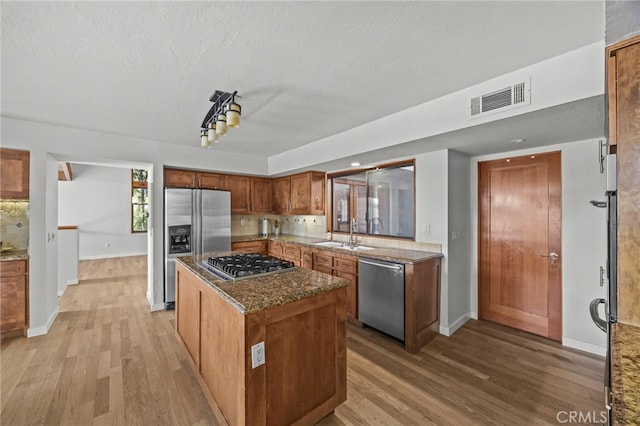 4 Woodhaven, Laguna Niguel, CA 92677 - kitchen with stainless steel appliances, light wood-style floors, a kitchen island, dark stone counters, and a textured ceiling