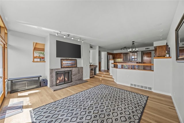 4 Woodhaven, Laguna Niguel, CA 92677 - living room featuring track lighting, light wood-type flooring, a tile fireplace, and a chandelier
