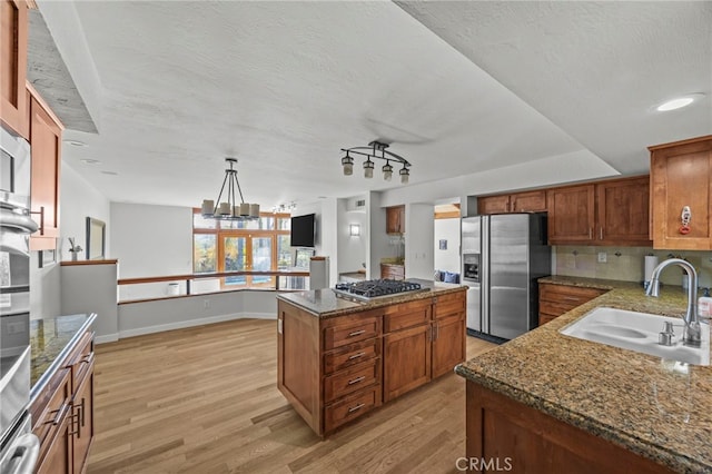 4 Woodhaven, Laguna Niguel, CA 92677 - kitchen featuring appliances with stainless steel finishes, light wood-style floors, a kitchen island, tasteful backsplash, and brown cabinetry