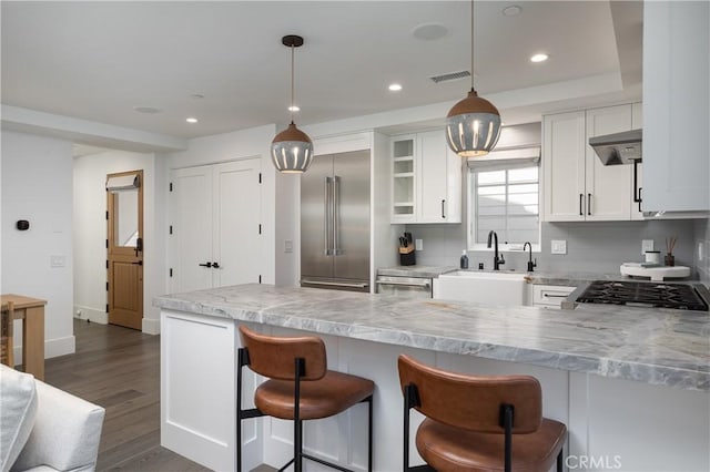 7141/2 Iris Ave, Newport Beach, CA 92625 - kitchen featuring built in fridge, a breakfast bar area, white cabinetry, a peninsula, and dark wood-type flooring