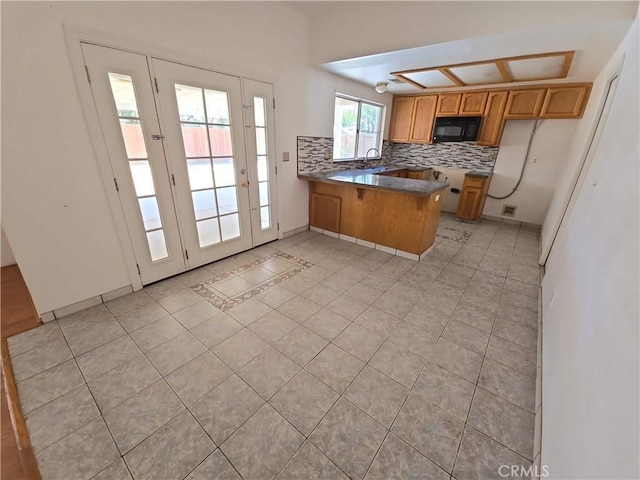 568 Walnut Ct, Kerman, CA 93630 - kitchen with a peninsula, black microwave, decorative backsplash, and light tile patterned floors