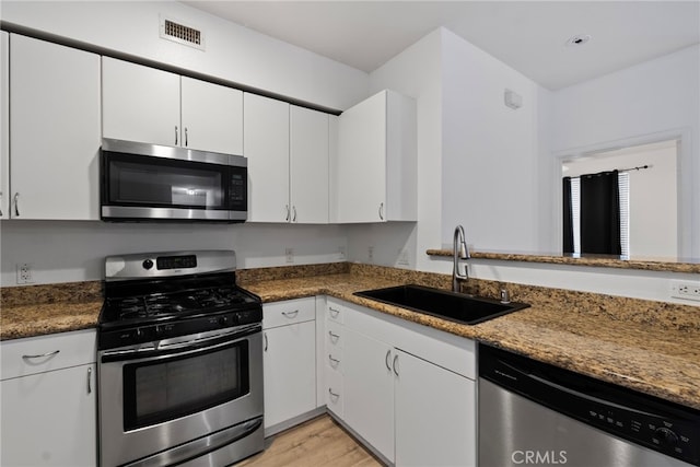 1801 E Katella Ave Unit 1091, Anaheim, CA 92805 - kitchen with appliances with stainless steel finishes, white cabinetry, light wood finished floors, and stone countertops