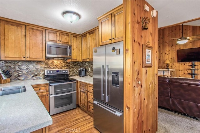 27657 Peninsula Dr, Lake Arrowhead, CA 92352 - kitchen featuring appliances with stainless steel finishes, brown cabinets, open floor plan, wooden walls, and a textured ceiling
