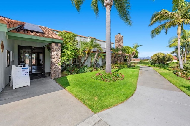 1866 Forestdale Dr, Encinitas, CA 92024 - view of front of property with roof mounted solar panels, a tiled roof, a front yard, and stone siding