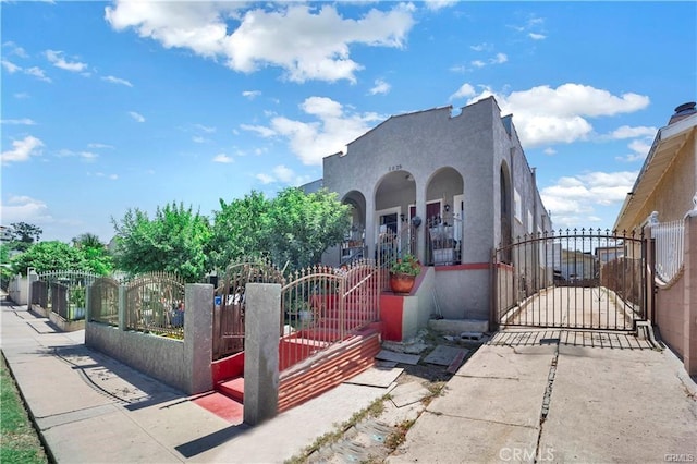1026 Sentinel Ave, Los Angeles, CA 90063 - mediterranean / spanish home featuring a gate, a fenced front yard, a porch, and stucco siding