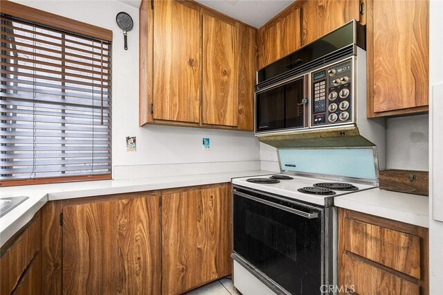 12555 Euclid St Unit 2, Garden Grove, CA 92840 - kitchen with white electric stove, brown cabinets, light countertops, and black microwave