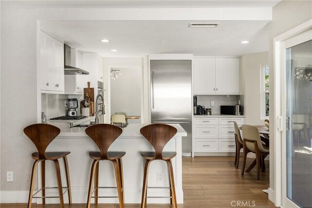 5 Bergamo, Irvine, CA 92614 - kitchen featuring wall chimney exhaust hood, stainless steel built in fridge, a breakfast bar area, backsplash, and recessed lighting