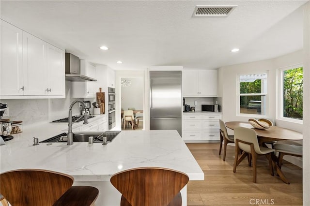 5 Bergamo, Irvine, CA 92614 - kitchen with stainless steel appliances, a peninsula, light wood finished floors, light stone counters, and recessed lighting
