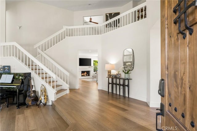 5 Bergamo, Irvine, CA 92614 - foyer featuring wood-type flooring, ceiling fan, stairway, a warm lit fireplace, and a towering ceiling