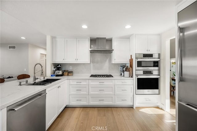 5 Bergamo, Irvine, CA 92614 - kitchen with stainless steel appliances, wall chimney exhaust hood, light wood finished floors, white cabinetry, and recessed lighting