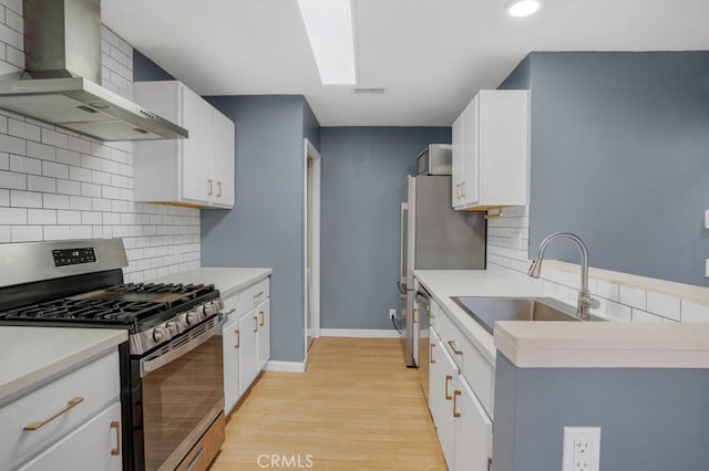 2367 Archwood Ln Unit 171, Simi Valley, CA 93063 - kitchen with stainless steel range with gas stovetop, wall chimney exhaust hood, light wood finished floors, decorative backsplash, and light countertops