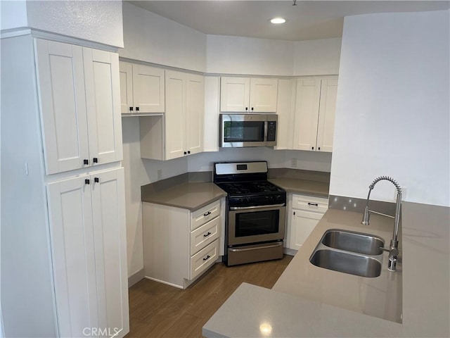 14914 Hamlin St Unit 105, Van Nuys, CA 91411 - kitchen with appliances with stainless steel finishes, dark wood-style floors, white cabinets, recessed lighting, and a peninsula