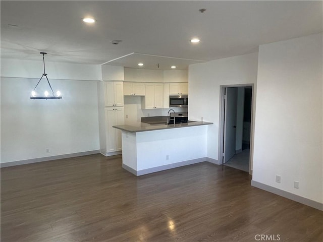 14914 Hamlin St Unit 105, Van Nuys, CA 91411 - kitchen featuring stainless steel microwave, a peninsula, white cabinets, dark wood-type flooring, and recessed lighting